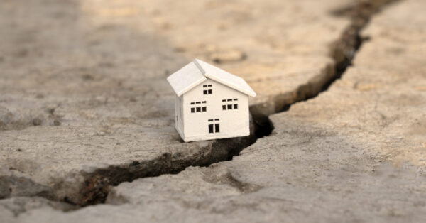 The house fell into a crack during an earthquake. Earthquake home insurance concept Real estate fall